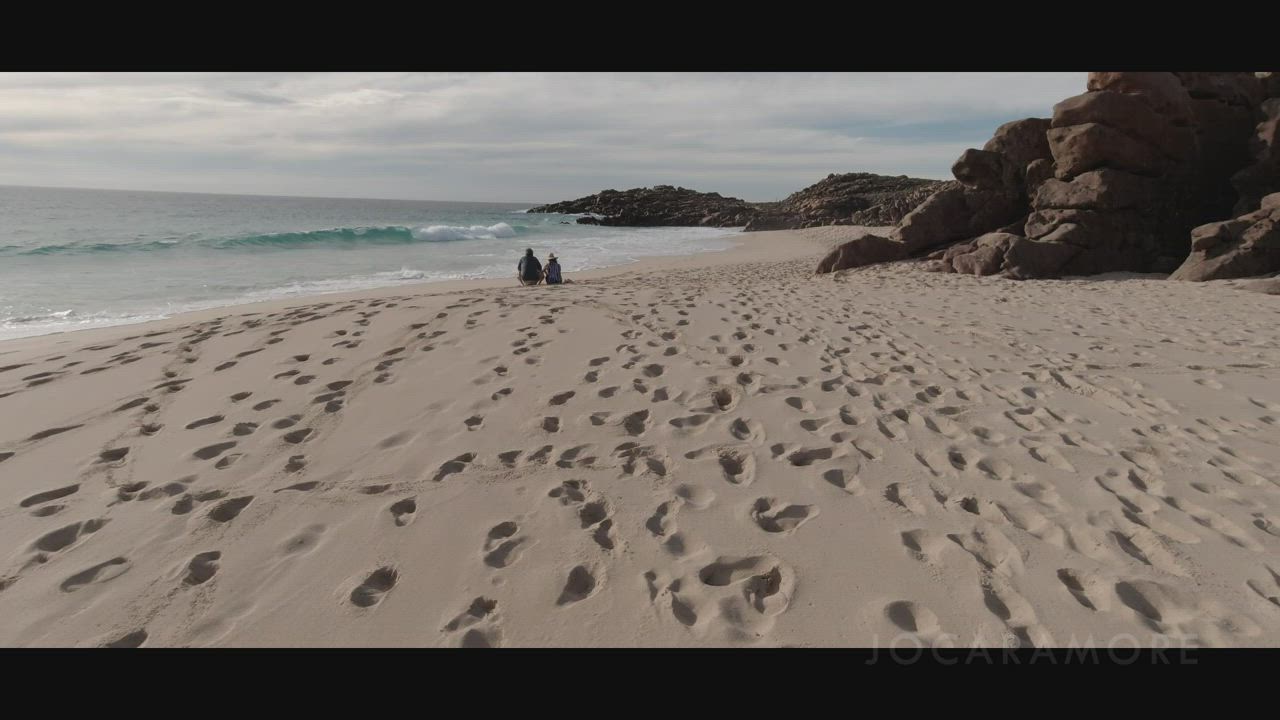 Another public beach handjob, with people in the distance...