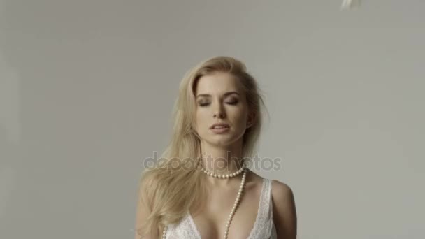 Mulher jovem e bonita loira isolada em pétalas de rosa de fundo cinza com queda